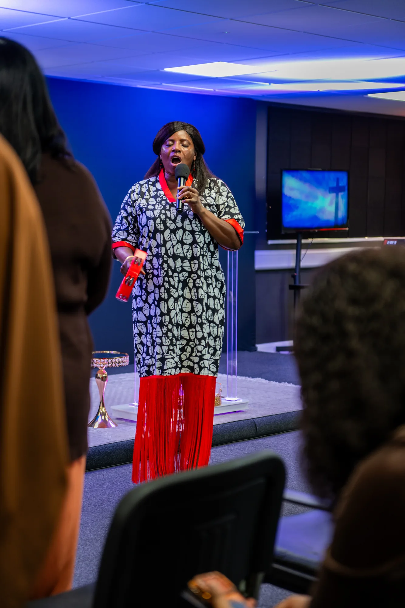 A woman holding a microphone and tambourine during a church service